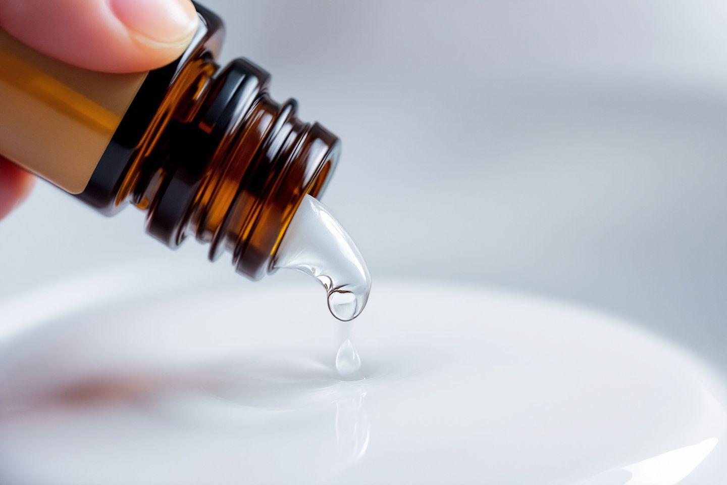Gros plan sur un flacon d'huile essentielle avec une goutte qui coule.